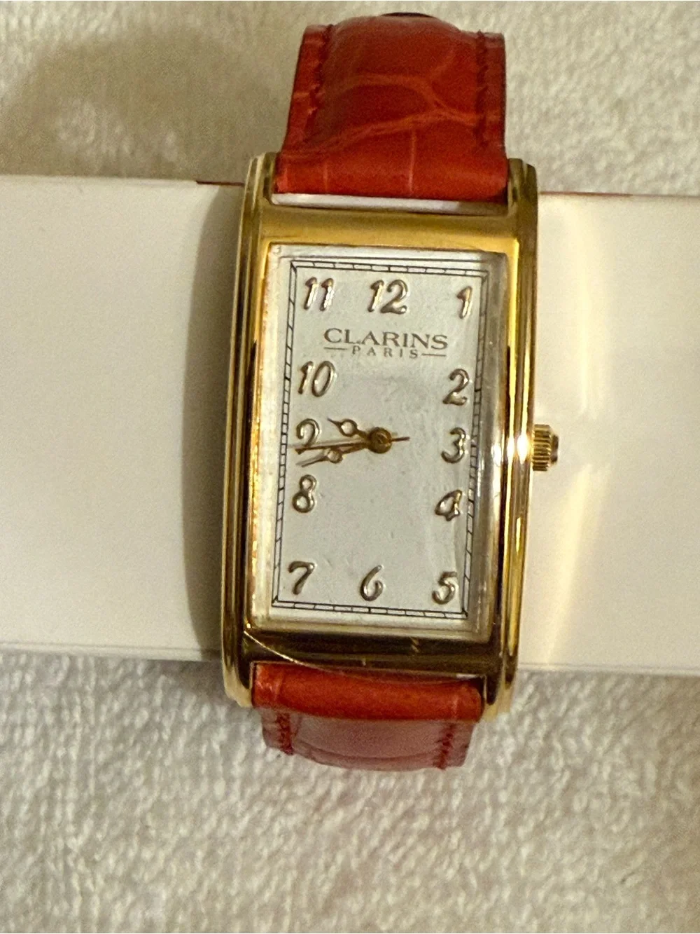 Clarins Gold-Tone Rectangular Watch with Red Strap and White Dial